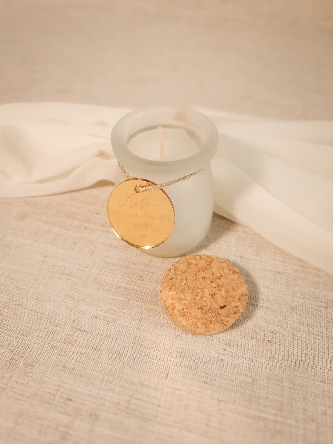 Kerze im Glas mit Korkdeckel und goldfarbener Medaille – Seitenperspektive
