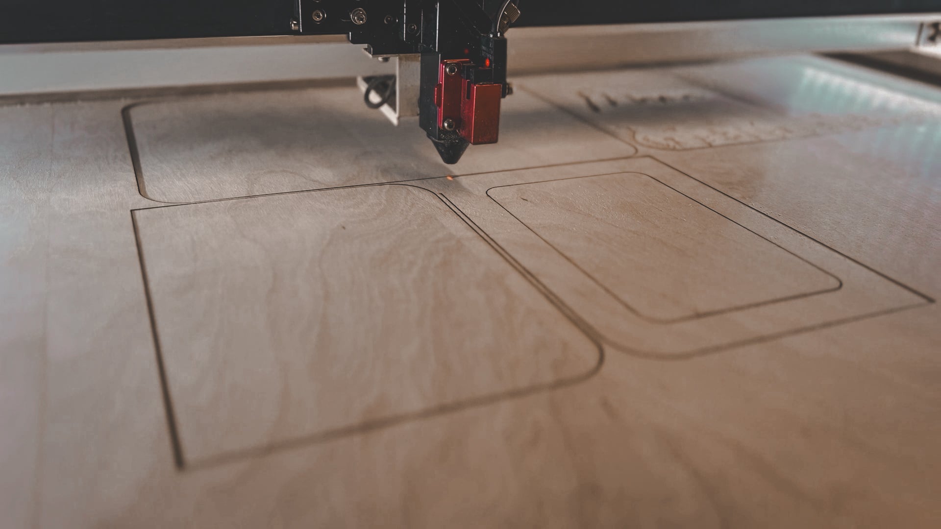 Lasergravur in der eigenen Werkstatt: eine Lasermaschine schneidet Formen aus einer Holzplatte für personalisierte Geschenke